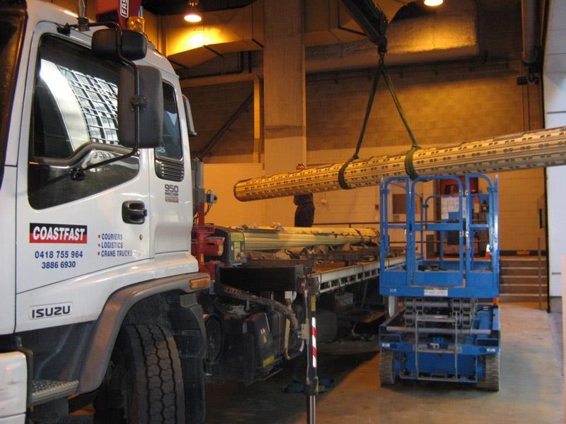 A crane truck lifting a large roller door curtain into a building