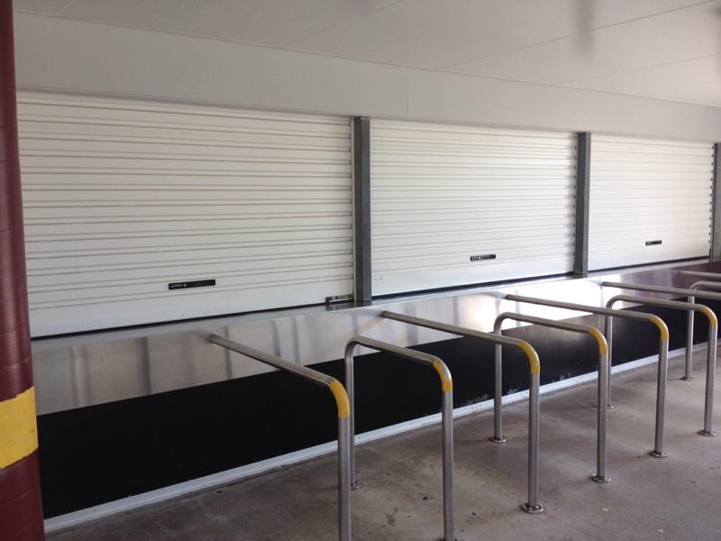 Row of white roller shutters behind steel bollards